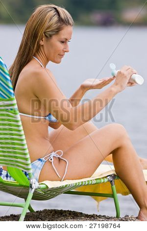 Femme, application de lotion écran solaire à la plage