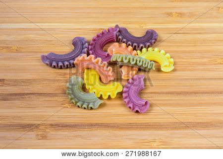 Several Uncooked Colored Short Curved And Ruffled Pasta Also Known As Creste Di Gallo Pasta Close-up