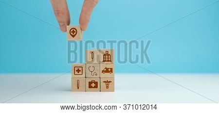 Wooden Blocks With The Healthcare Medical Symbol Arranged A Man Is Holding The Top One.