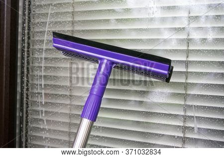 Cleaning Window Using A Violet Squilgee To Wash Glass. Housekeeping Concept.