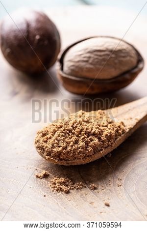 Whole Nutmeg Nuts And A Spoon With Nut Powder On Rustic Wooden Table Close-up. Indian Spice.