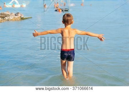 Little Boy Go Swimming Into The Water, Back View. Freedom, Lifestyle And Travel. Family Summer Vacat