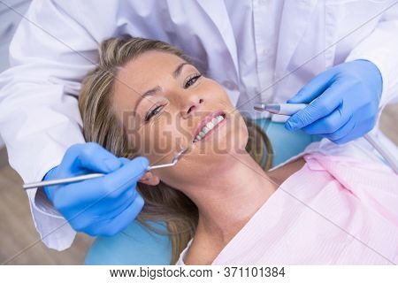High angle portrait of woman by dentist dolding tool at medical clinic