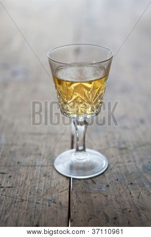 Bicchiere di vino bianco in un vetro antico, posizionato su un tavolo in legno vecchio.