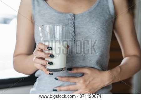 Lactose Intolerance Concept. Woman Holding A Glass Of Milk And Having A Stomachache.
