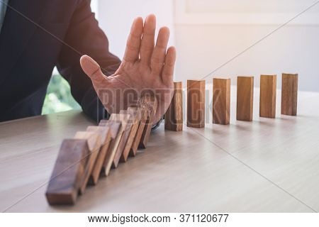 Protection Finance From Domino Effect Concept. Hands Stop Domino Effect Before Destroy Stack Of Mone