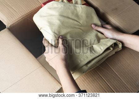 Organize Stuff Before Moving House. Close Up Hands Of People Putting Unwanted Used Clothes To Carton
