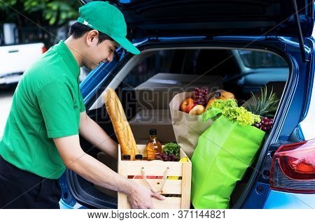 Asian Delivery Man In Green T-shirt Delivering Food, Fruit, Joice And Vegetable To Home - Online Gro