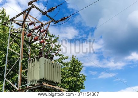 Energy And Technology: Electric Pole By The Road With Power Lines Cables, Transformer Against The Bl