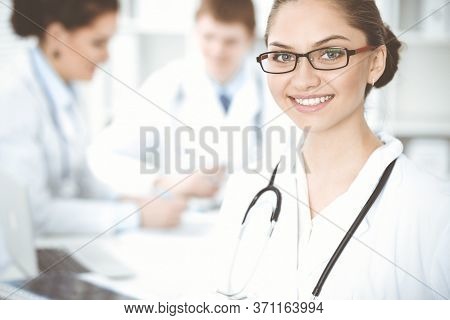 Happy Smiling Woman-doctor Sitting And Looking At Camera At Meeting With Medical Staff . Medicine Co