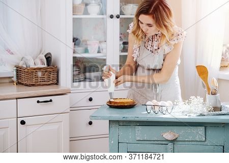 Cute Woman Immersed In Cooking Squeesing Whipping Cream On A Small Cake