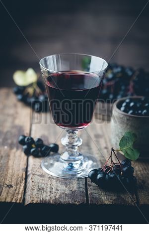 Homemade Black Chokeberry Wine Or Liqueur With Ripe Berries On Wooden Background