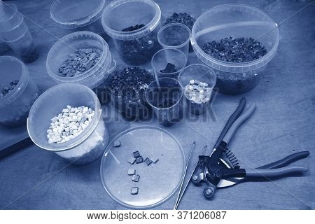 Smalt Of Different Colors In Plastic Containers On The Table. Photo Toned In Classic Blue. Near The 