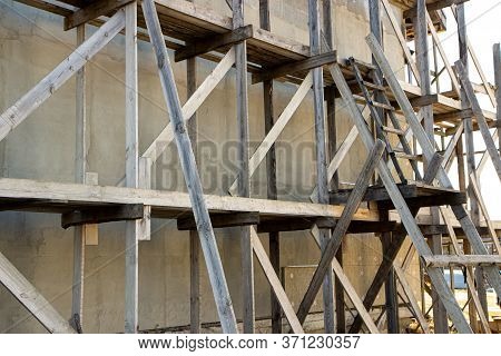 Wooden Scaffolding During The Construction Of A Large House Or Cottage Outside