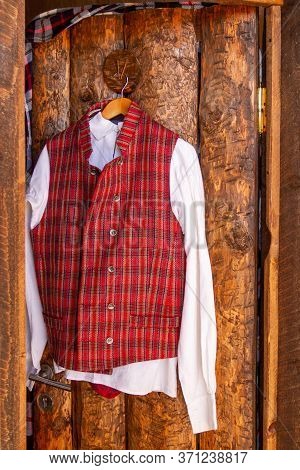 Male National Costume With White Shirt And Red Coat Hanging On Wooden Door