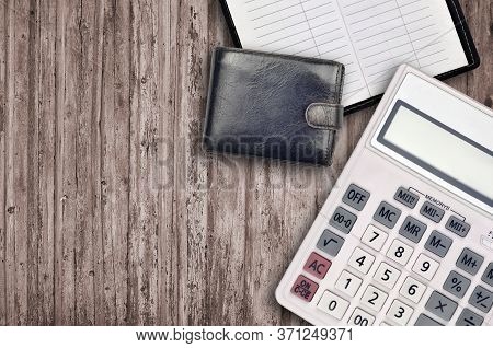 Office Flat Lay Composition With Calculator, Address Book And Black Purse On Brown Wooden Table Back