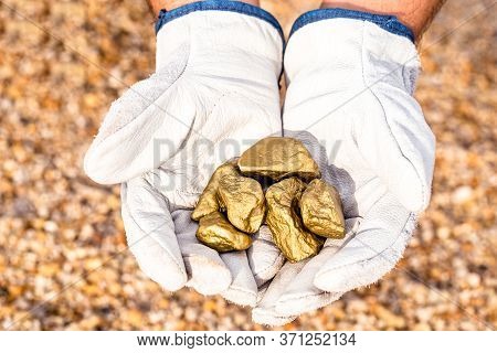 Miner Hand Holding Stones From Another, Gold Mineral Extraction, Precious Stone Exploration Concept.