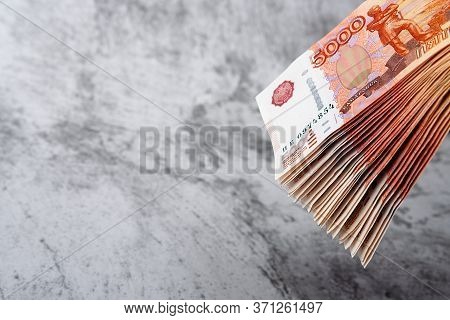 Russian Cash Banknotes Of Five Thousand Rubles, The Bundle Hangs On A Gray Background.