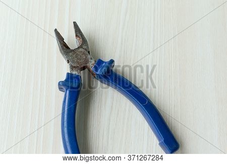 Close Up Of Yellow Pliers And Nail On Wooden Table. Diagonal Pliers With Uninsulated Handles.