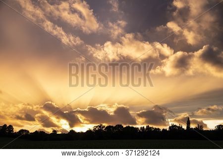 Beautiful Summer Sunset Sky With Colorful Vibrant Clouds And Sun Beams Across Whole Sky