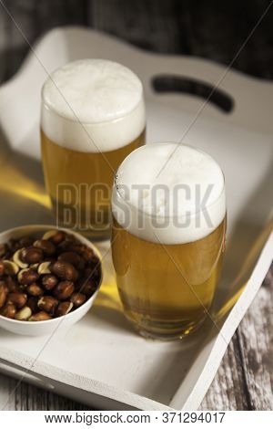 Two Glasses Of Beer With A Bowl Of Peanuts