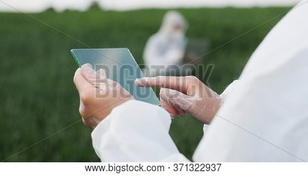 View Over Shoulder Of Farmer Ecologist In Protective Suit Tapping On Glass Transparent Screen. Close