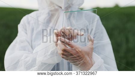 Close Up Of Female Farmer Ecologist In Protective Suit Tapping On Glass Transparent Screen. Futurist