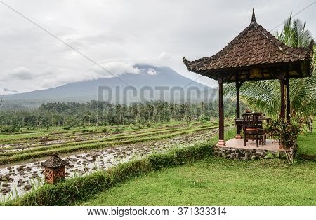 Gazebo With Table And Chairs By The Rice Fields With View On Agung Volkano On A Cloudy Day In Bali, 