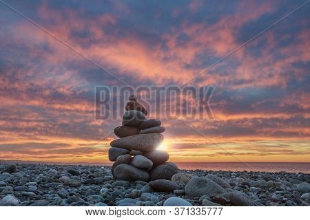 Pebbles Stack On Sea Rocky Beach With Sea And Colorful Sunset Sky Background