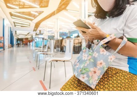 Woman Wear A Protective Mask And Use Smartphone While Sit On Chair Were Spaced Apart And Waiting Tim