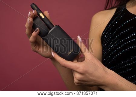 Tula, Russia - June 06 2020: Woman With E-cigarette. Heating Tobacco System Iqos Product Technologie