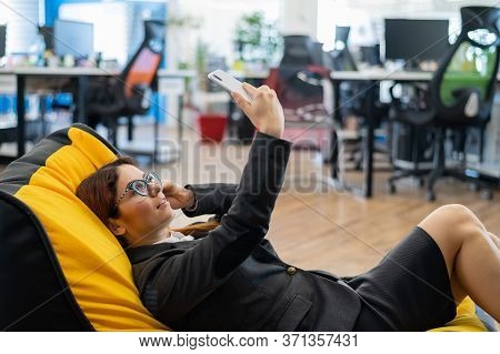 A Business Woman In A Suit Is Resting While Sitting In A Comfortable Chair Bag And Taking A Selfie. 