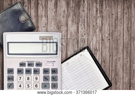 Office Flat Lay Composition With Calculator, Address Book And Black Purse On Brown Wooden Table Back