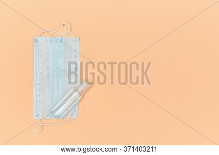 Face Mask, Unbranded Bottle For Antiseptic On Peach Backdrop, Copy Space. Preventive Measures. Covid