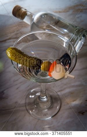 Dry Gin Martini Served Neat With Pickle Cocktail Stirrer And Bottle In Background