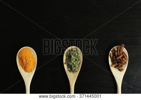 Three Wooden Spoons With Saffron, Oregano And Chillies From Above
