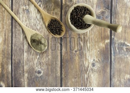 Black Peppercorns And Ground Black Pepper On Wooden Spoons