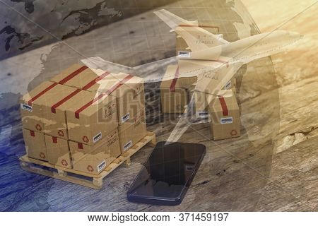 Packing Boxes Small Goods And Cell Phone With A Plane Flies Above World Map. Business Concept About 