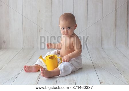 One Yeat Old Baby Girl Is Sitting On Wooden Backgroun In White Towel. After Bath Time.