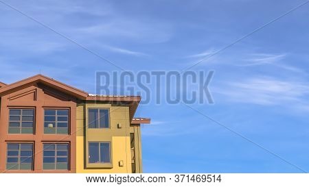Panorama Crop Home Exterior With Balconies And Multi Color Walls Against Blue Sky And Clouds