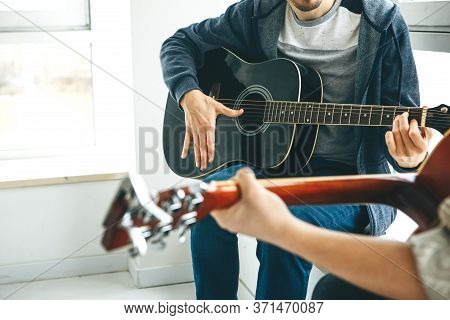 Learning To Play The Guitar. The Teacher Explains To The Student The Basics Of Playing The Guitar. I