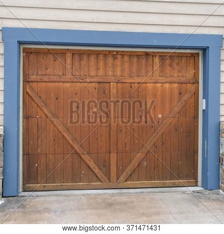 Square Brown Wood Garage Door With Blue Frame Flaned By Wall Mounted Vintage Lanterns