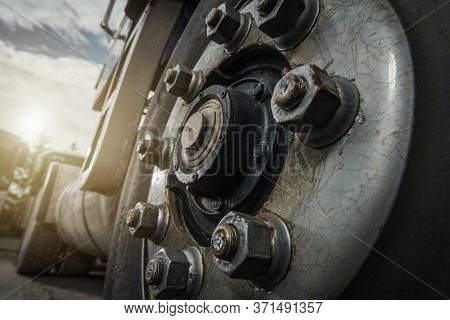 Heavy Duty Transportation Theme. Aged Semi Truck Wheel And Rusty Nuts Close Up. Industrial Concept.