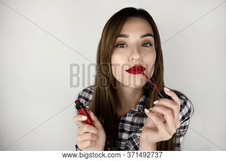 Brunette Young Woman Applying Red Lipstick On Her Lips Looking Sexy, Beauty And Makeup Isolated Whit