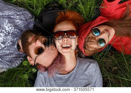 Smiling Young People In Sunglasses, Lying Down On A Green Grass, In The Park, Wear Sunglasses, Looki