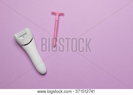 Women Epilator And Pink Razor On Purple Colored Paper Background, Top View With Copy Space.