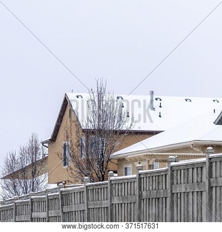 Square Snowy Houses On A Scenic Suburb Neighborhood Against Cloudy Sky In Winter