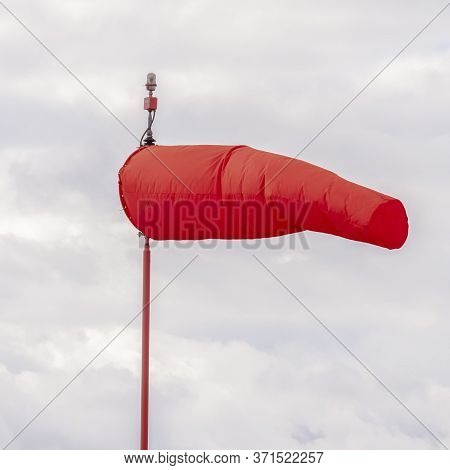 Square Crop Red Wind Sock At An Airport Blowing In The Wind