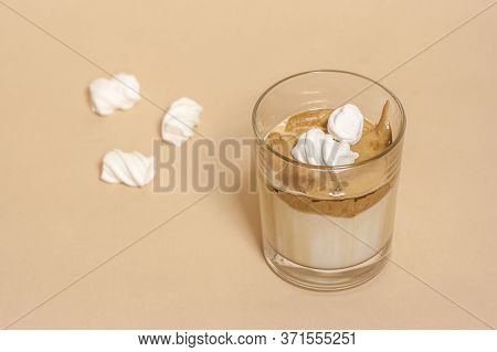 Dalgon Coffee In A Transparent Glass With Milk On A Pastel Background With Marshmallows.