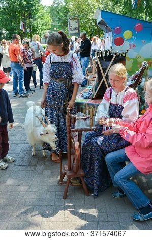 Chelyabinsk Russia June 12 2015 holiday Russia day a woman teaches a girl to work on an old spinning wheel in the Park to remember the traditions